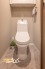 温水洗浄便座付きで、清潔かつ快適にお使いいただけるトイレ空間。上部には扉付き収納を備え、トイレットペーパーや掃除用品などもすっきりと収納可能です。